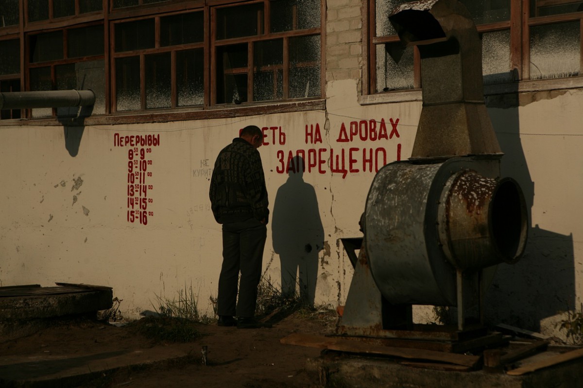 A man stands in front of a wall, waiting for his obligatory work hours to pass. Photo: Irina Popova/The Guardian.