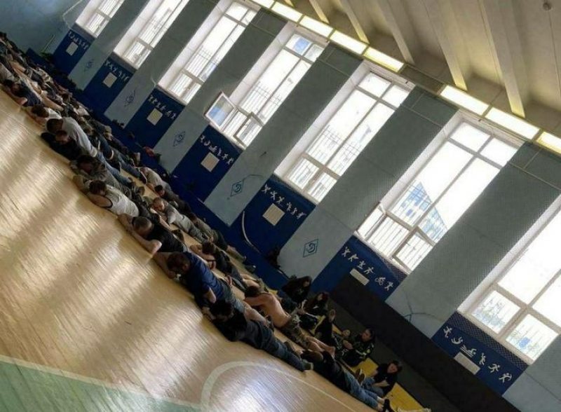 Detainees lying on the floor of a gym at a district police department